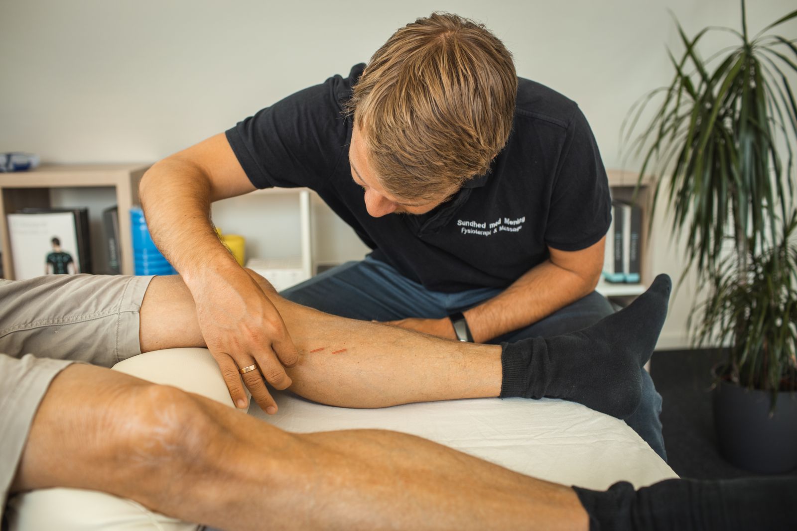 Fysioterapeut behandler mand med akupunktur